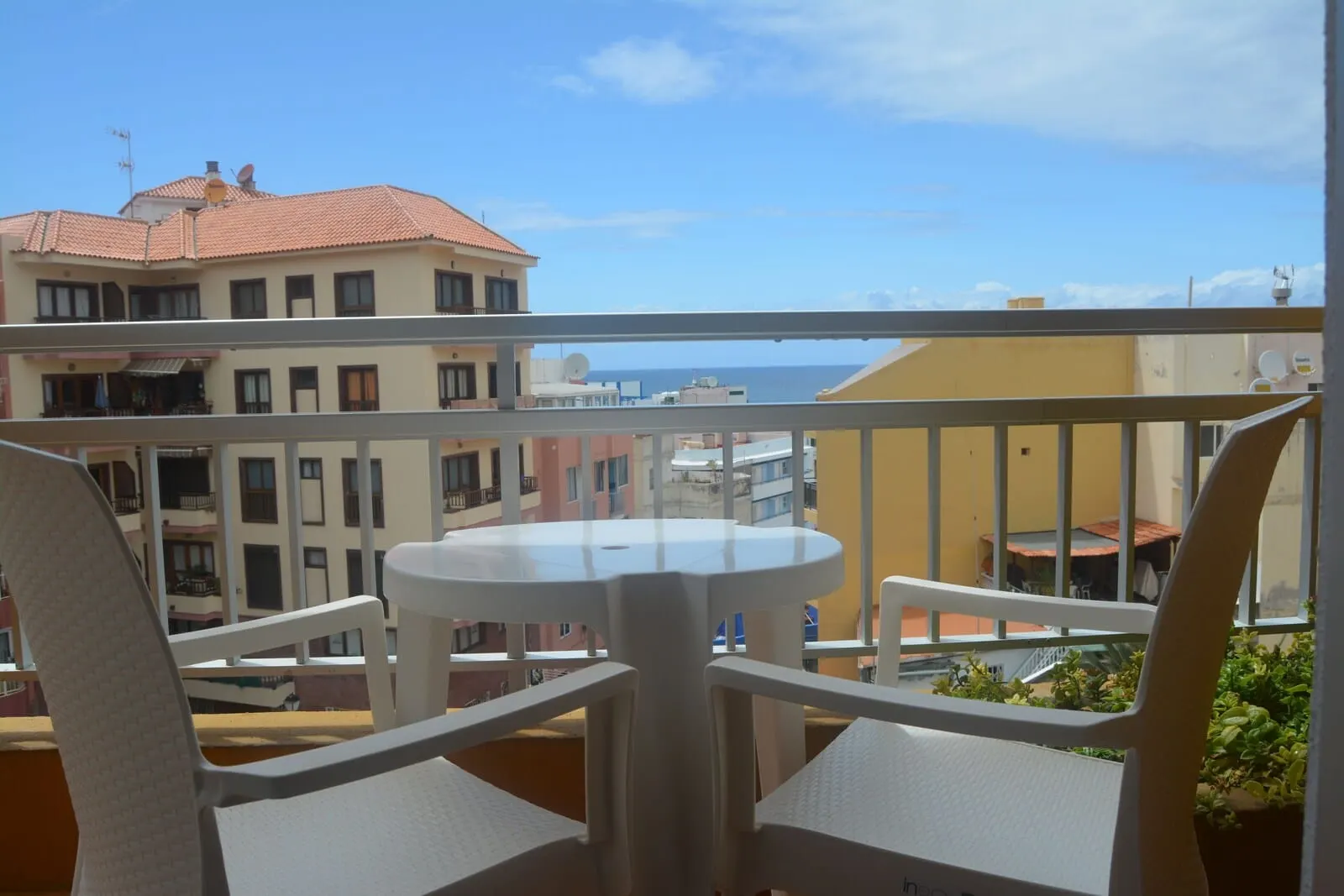 RF Apartamentos Bambi: A balcony with white chairs and a small table