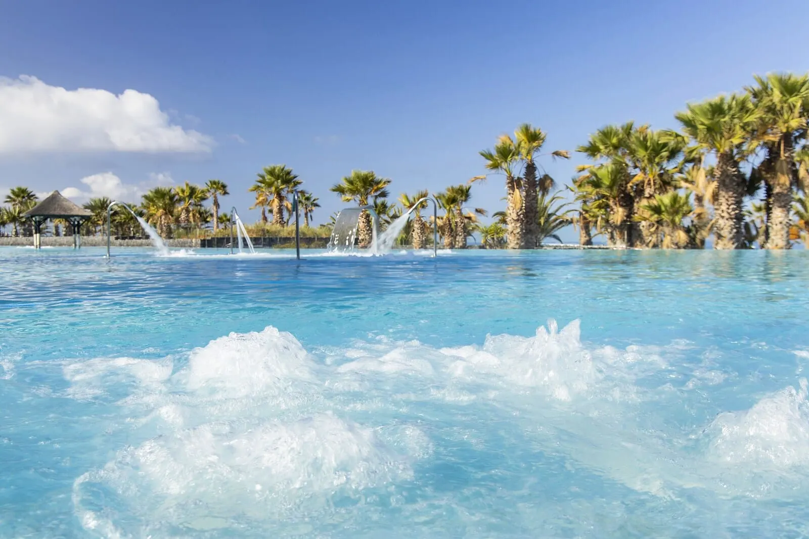 Gran Meliá Palacio de Isora: A pool with clear blue water, surrounded by palm trees and a gazebo