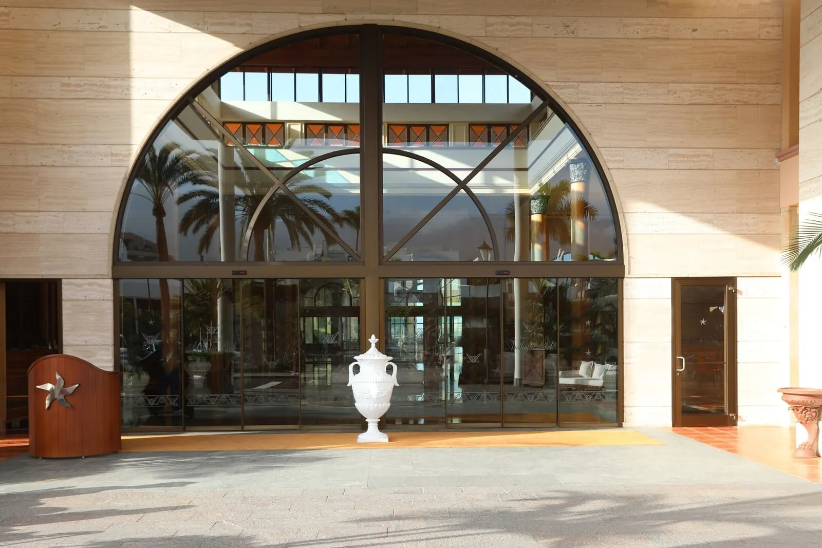 Iberostar Selection Anthelia: A large arched glass entrance with a central white urn, palm trees