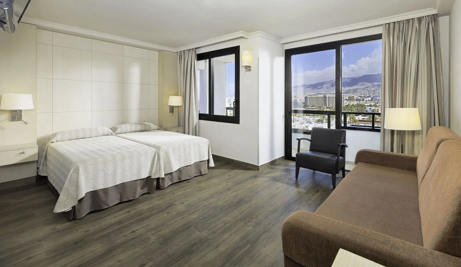 Spring Hotel Bitácora: A hotel room with two beds, a sofa, a chair, and a large window offering a city view