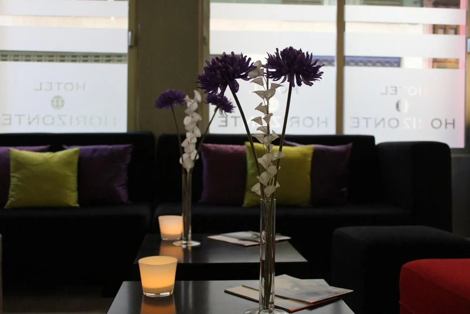 Nuevo Hotel Horizonte: A hotel lobby with a black sofa, a table with a candle, and vases with flowers