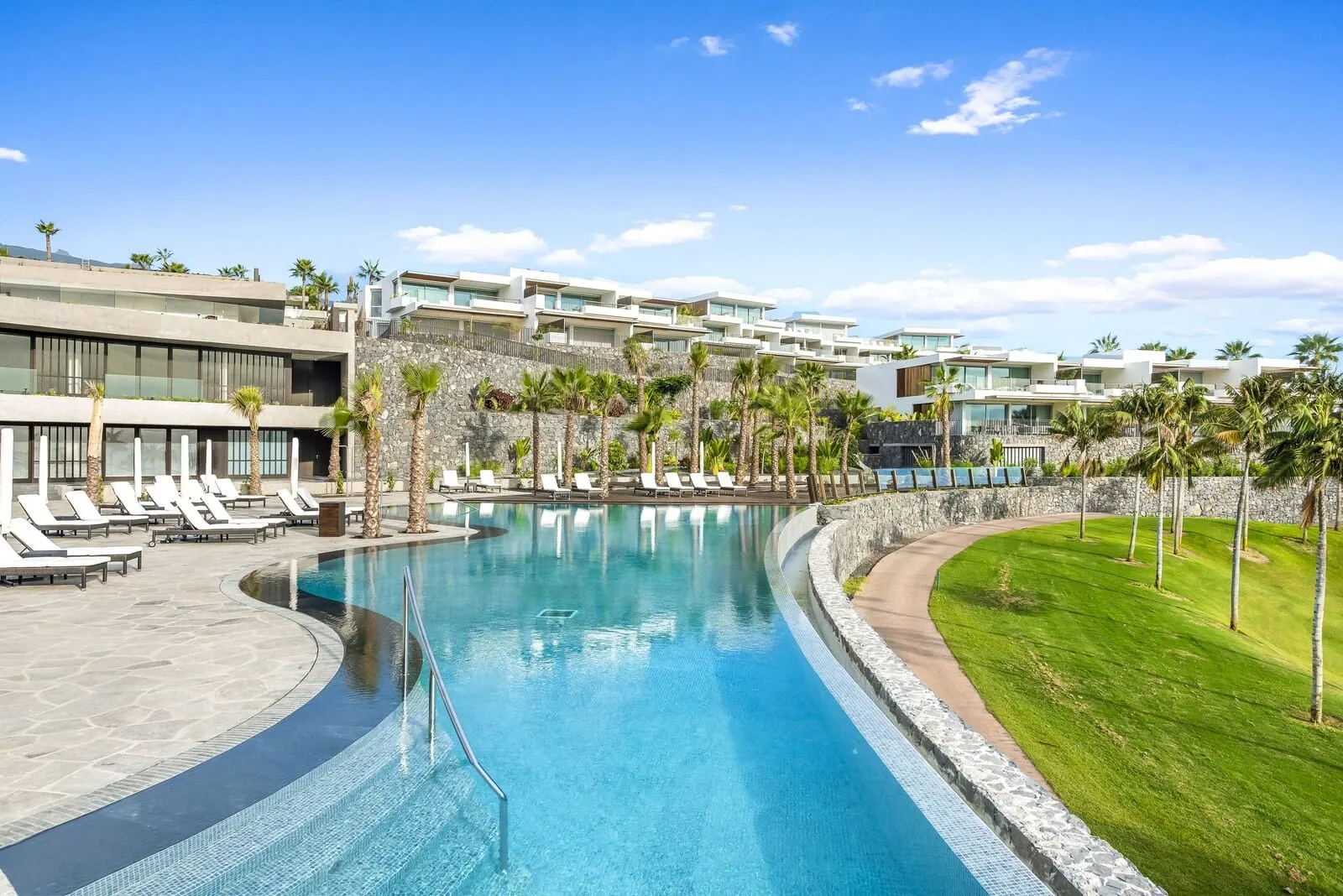 Los Jardines de Abama Suites & Villas: A modern hotel with a swimming pool, sun loungers, and palm trees