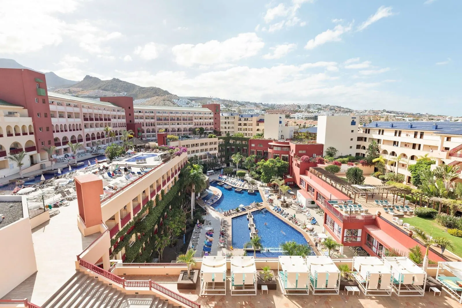Best Jacaranda: A hotel with multiple swimming pools, outdoor seating areas, and a mountainous backdrop