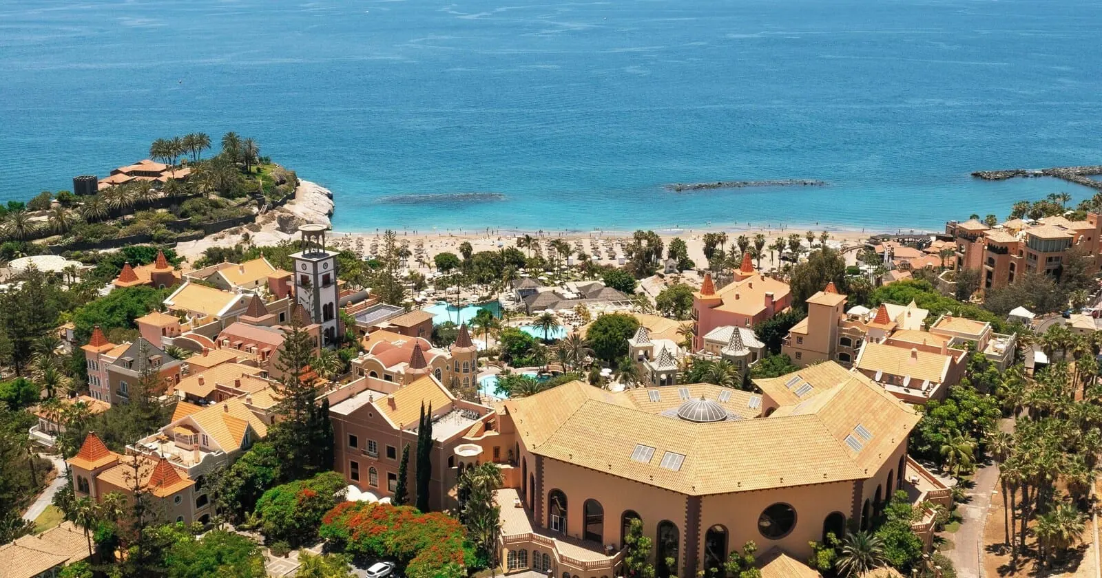 Bahía del Duque: A coastal resort with Mediterranean architecture, a beach, and a pool
