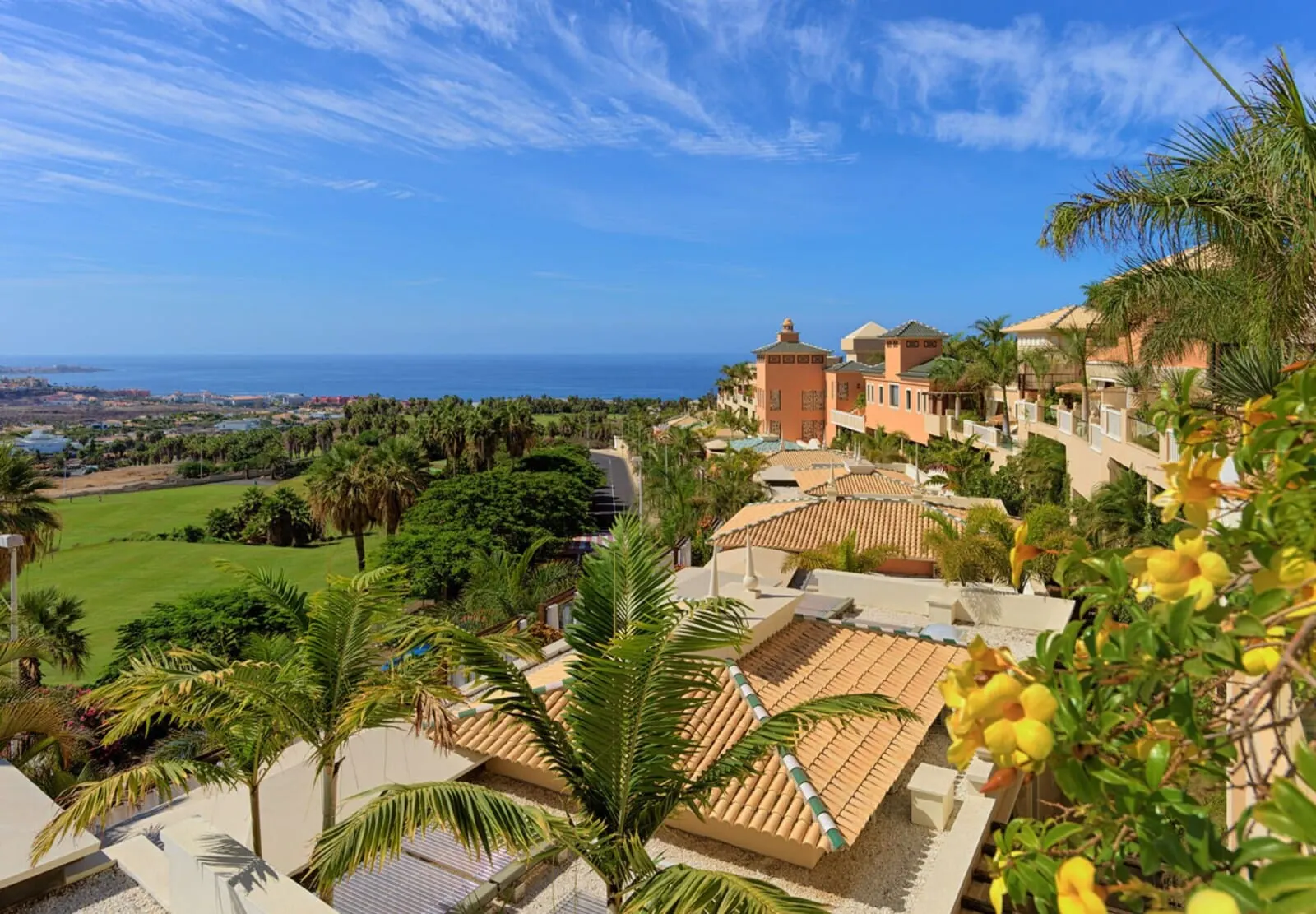 Royal Garden Villas & Spa: A coastal resort with terracotta-roofed buildings, palm trees, and a view of the ocean