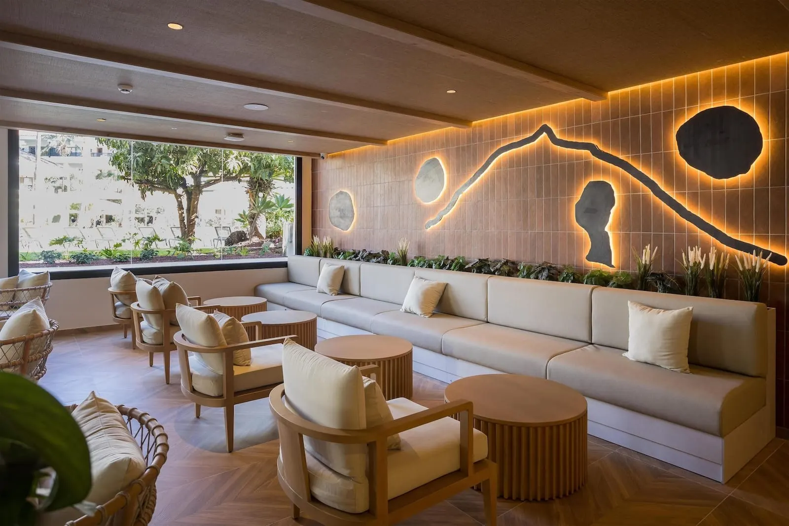 Radisson Resort & Residences Tenerife: A modern lounge area with a sofa, chairs, and round tables