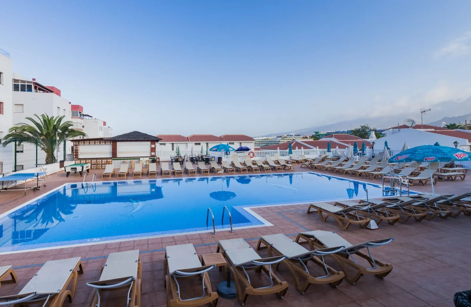 Tinerfe Garden: A swimming pool with sun loungers and umbrellas, surrounded by buildings with red roofs