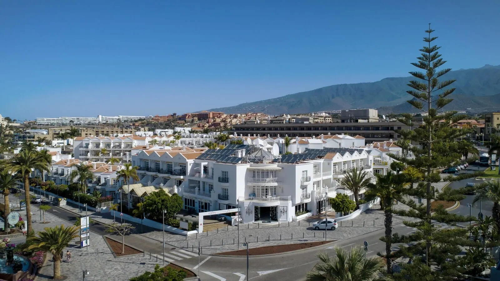 Apartamentos Parque del Sol: A coastal town with white buildings, a clear sky, and a mountain in the background