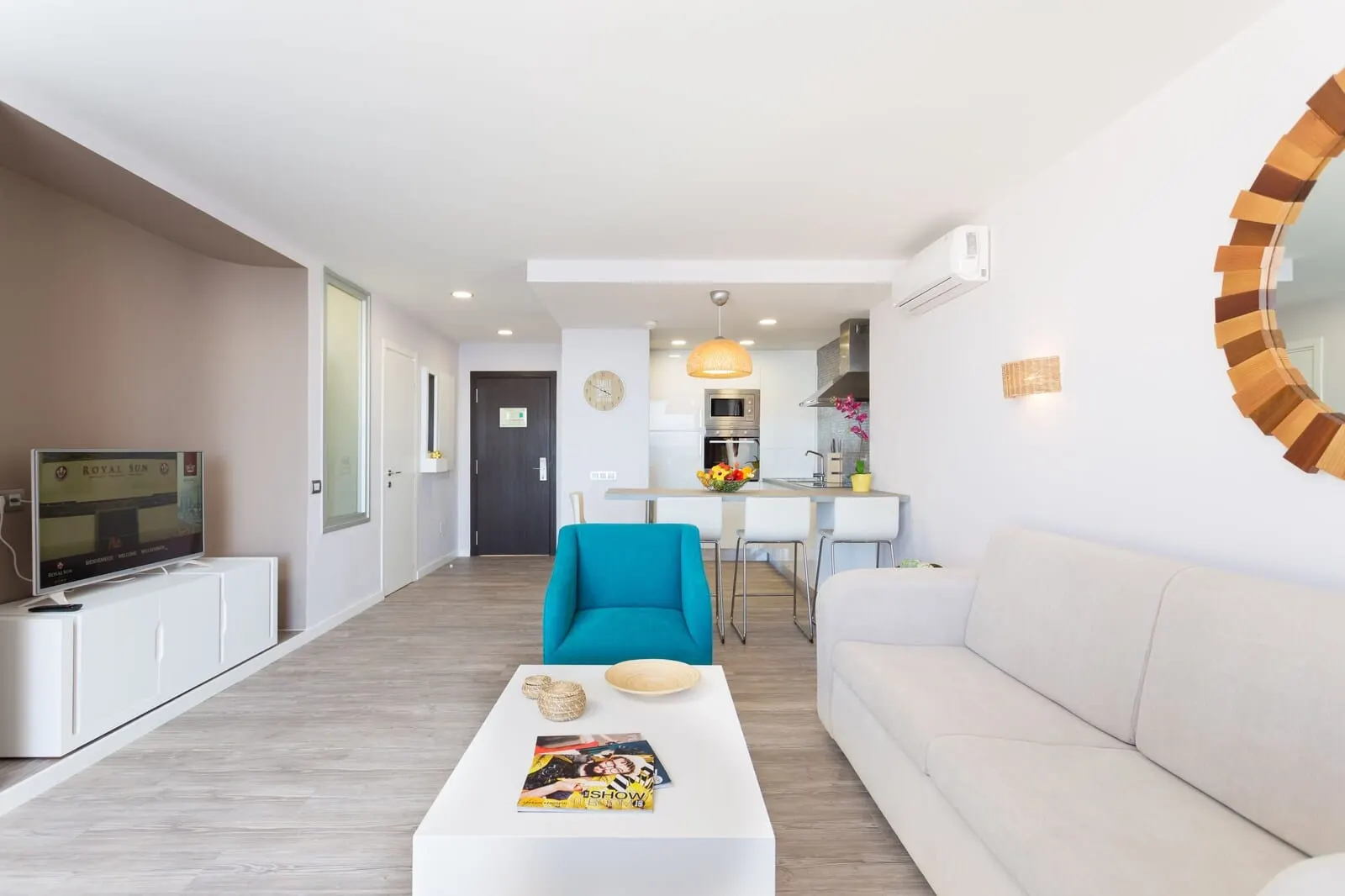 Royal Sun Resort: A modern living room with a sofa, a coffee table with a magazine, a blue armchair