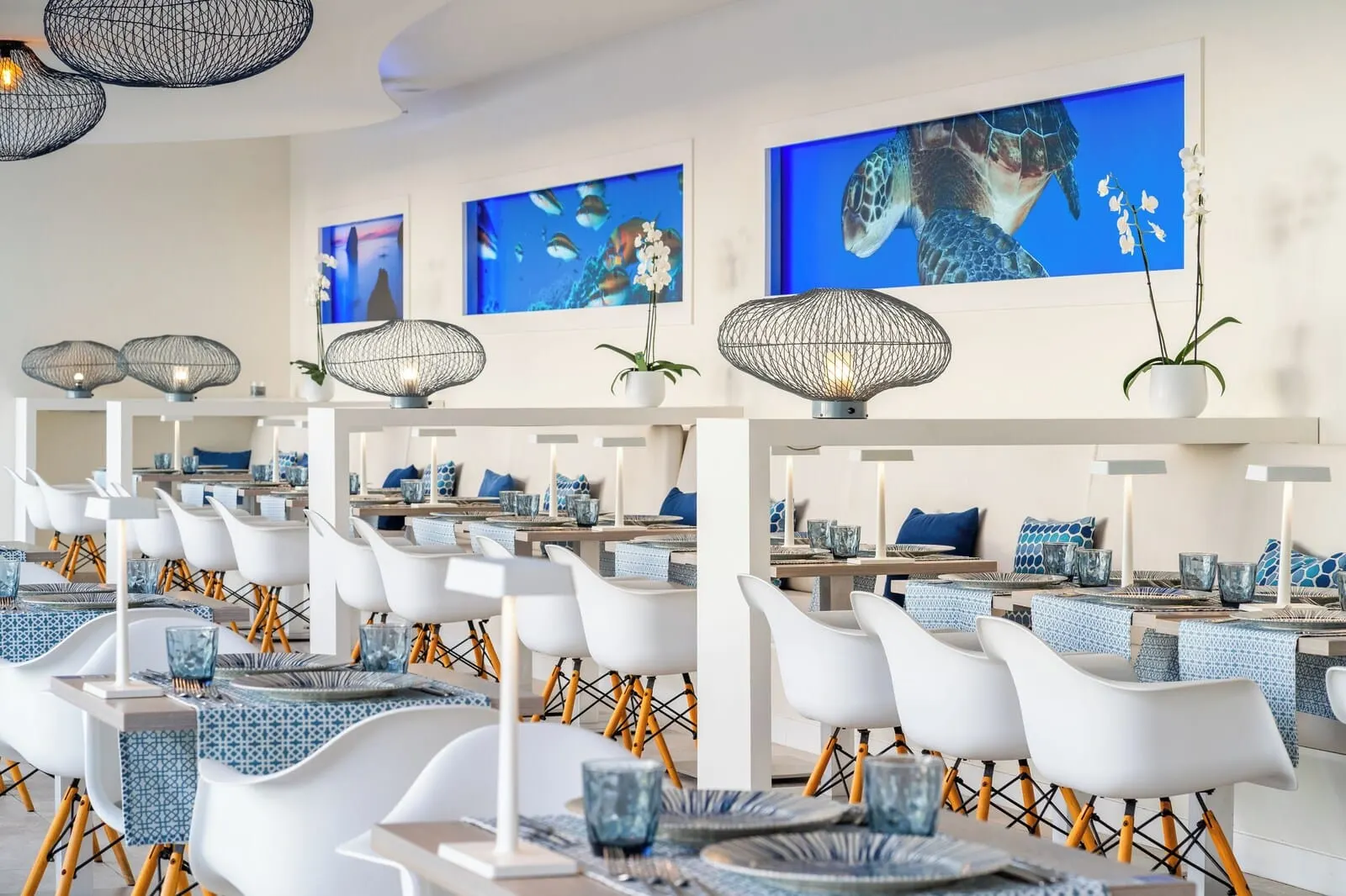 HOVIMA Cool Costa Adeje: A modern dining area with white chairs, blue tablecloths, and overhead wire lamps