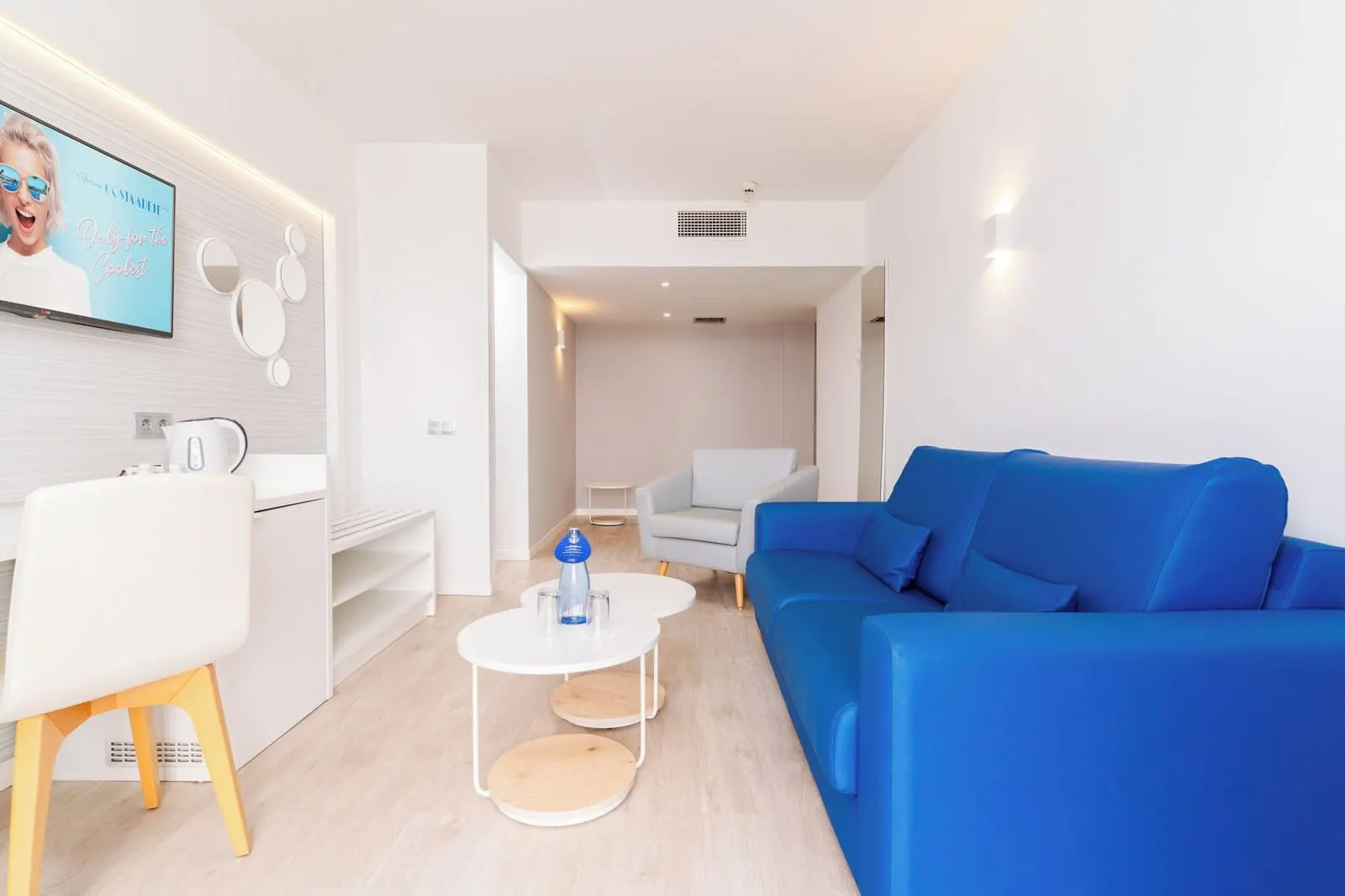 HOVIMA Cool Costa Adeje: A modern living room with a blue sofa, a white coffee table, a white chair