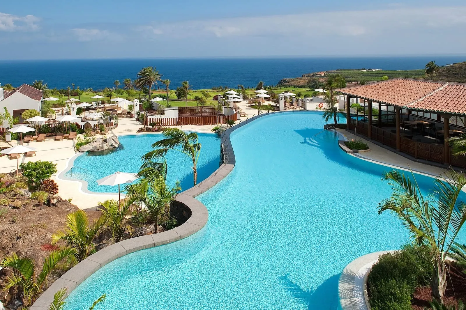 Hacienda del Conde Meliá Collection Golf & Spa: A resort pool with a curved design, surrounded by palm trees and lounge chairs