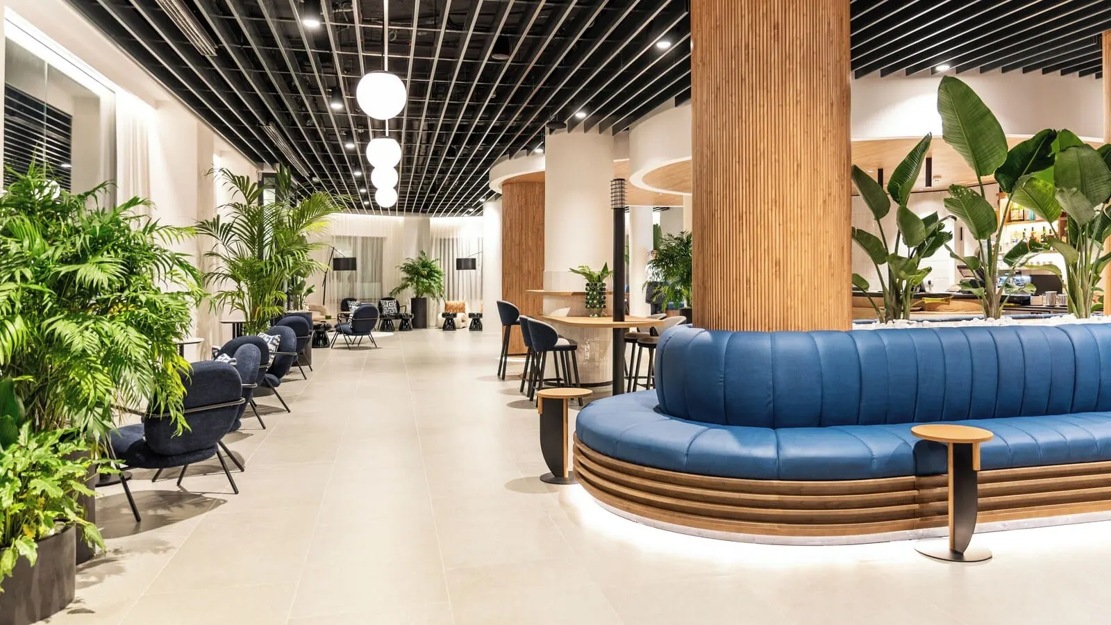 Barceló Santa Cruz Contemporáneo: A modern lounge area with a blue sofa, black chairs, and potted plants