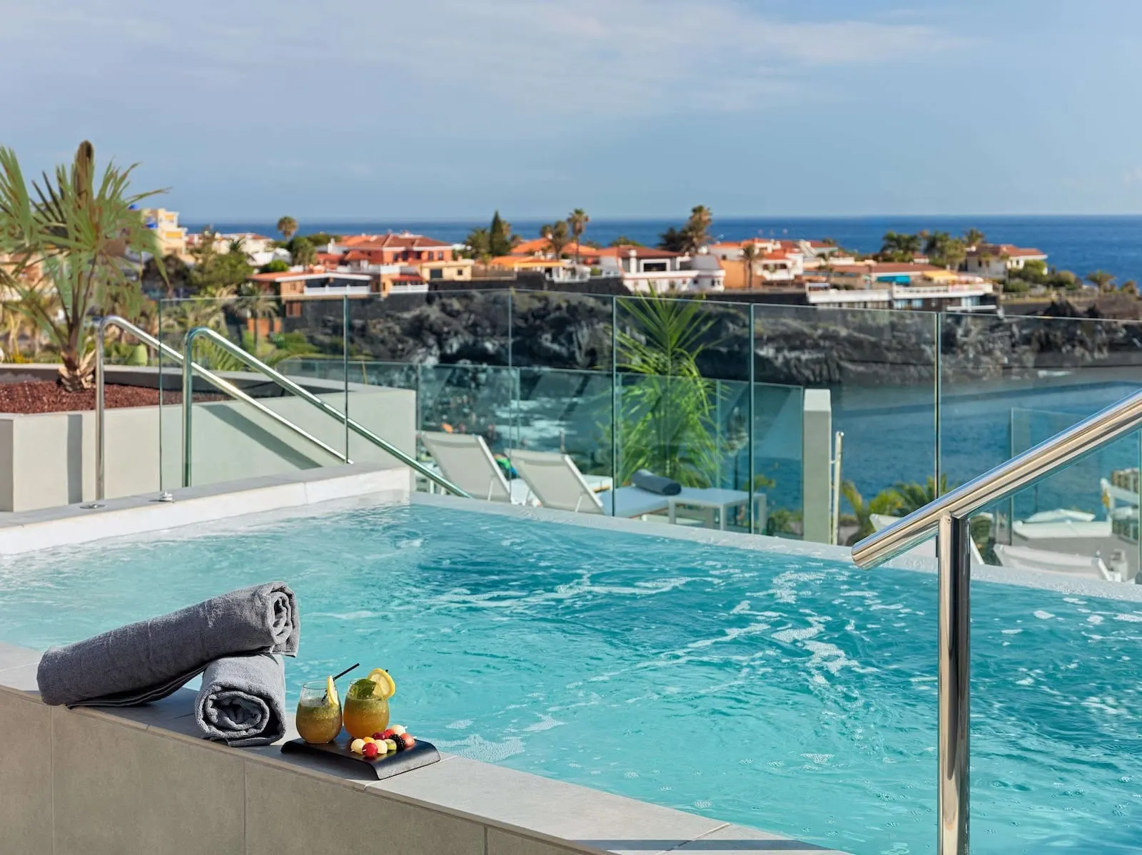 Landmar Playa la Arena: A pool with a glass railing, a towel, and two drinks on the edge