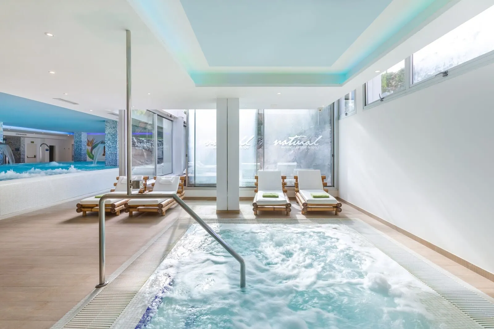 Alexandre Troya: A modern indoor pool area with a hot tub, lounge chairs