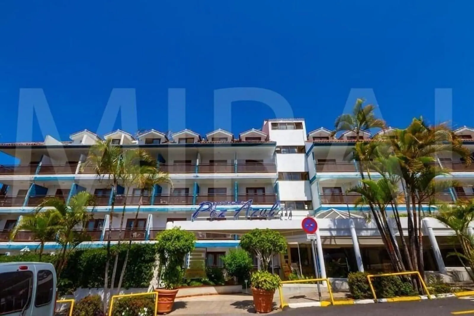 Apartamentos Pez Azul: A multi-story hotel with balconies, palm trees, and a clear blue sky