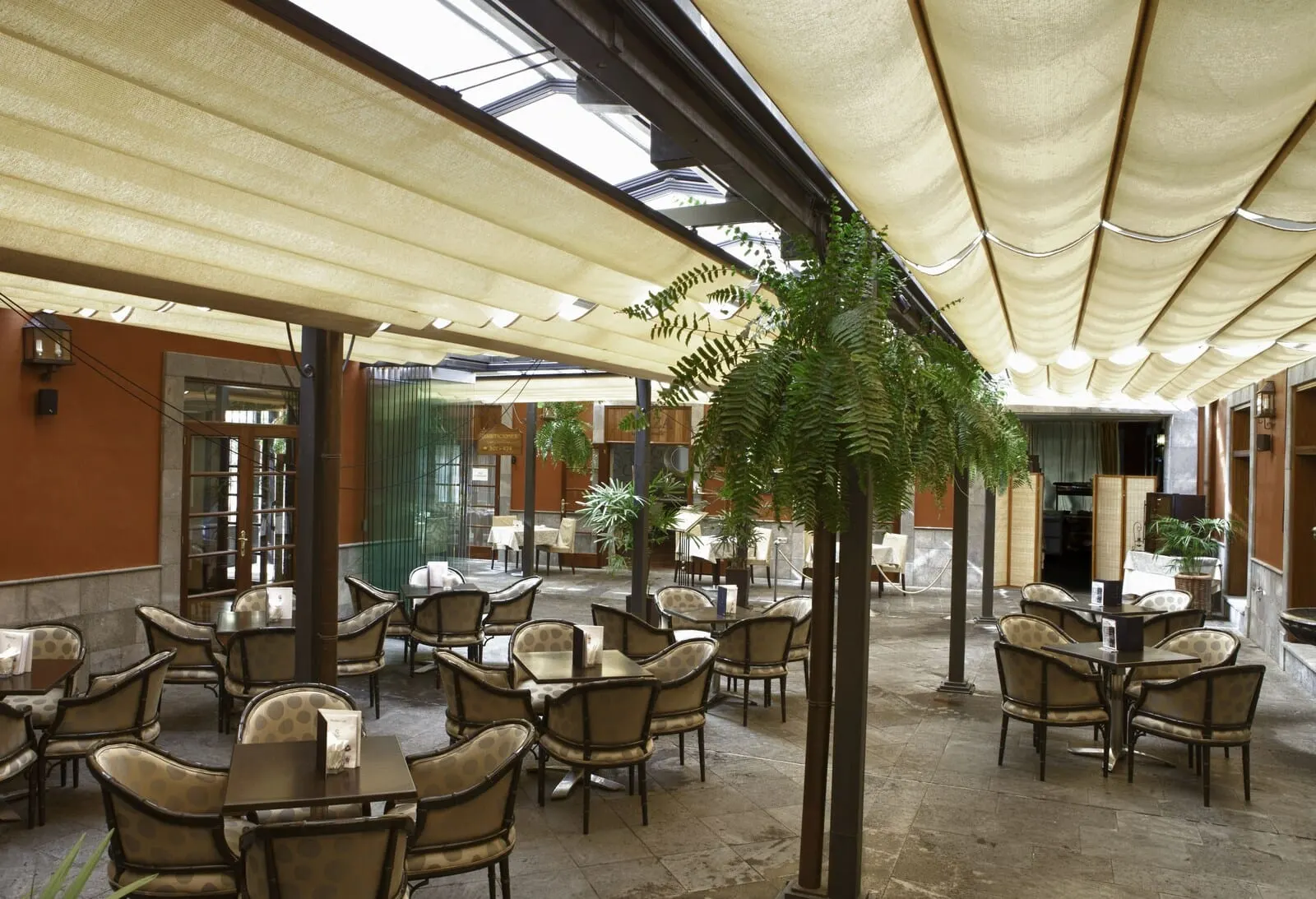 Laguna Nivaria Hotel & Spa: A spacious outdoor café area with multiple tables and chairs, shaded by large umbrellas