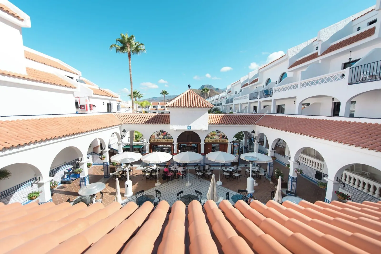 Ona Beverly Hills Heights: A courtyard with outdoor seating, palm trees, and a central building with arches