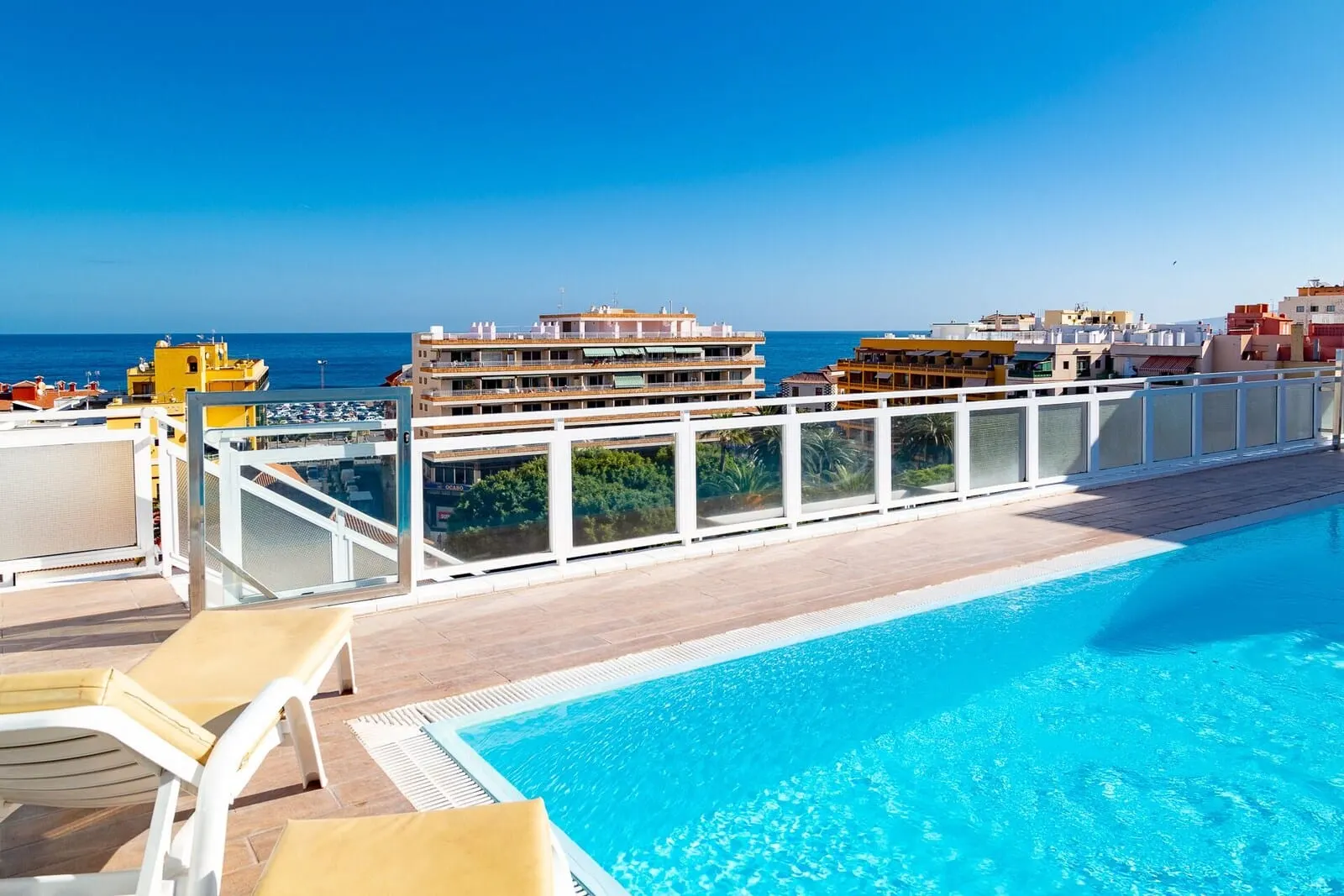Hotel Tropical: A rooftop pool with a clear view of the ocean and buildings in the background