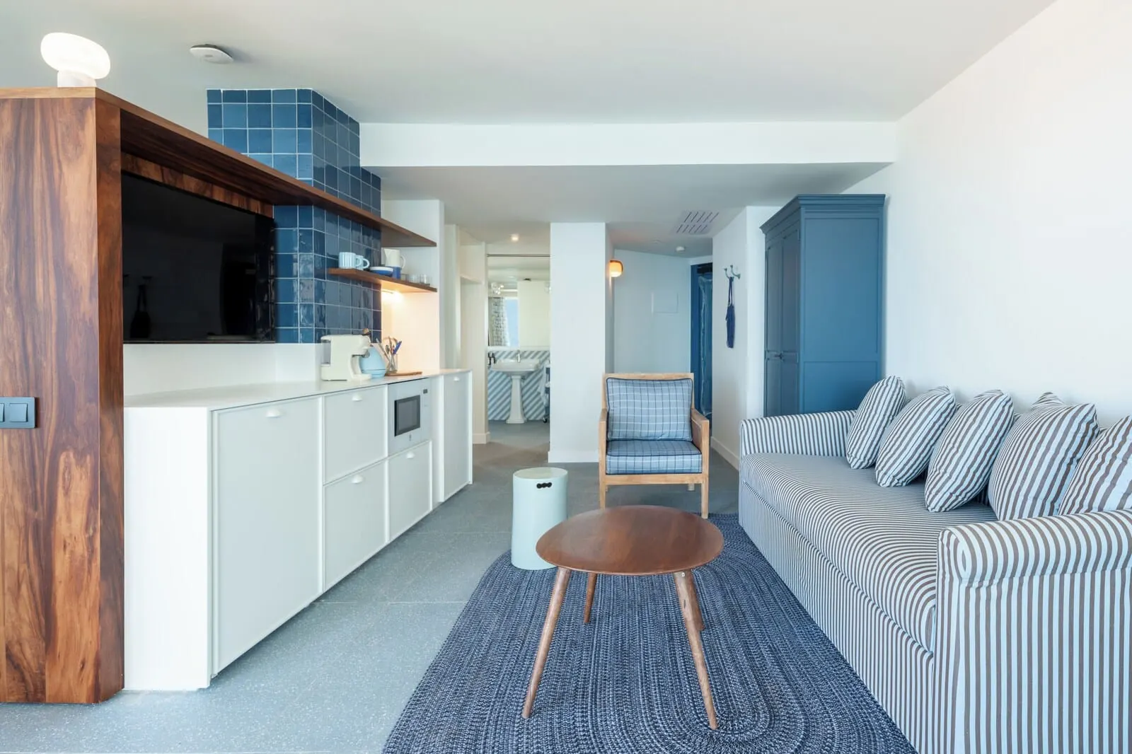 The Salmar: A modern kitchen with white cabinets, a wooden accent wall, and a blue tiled backsplash