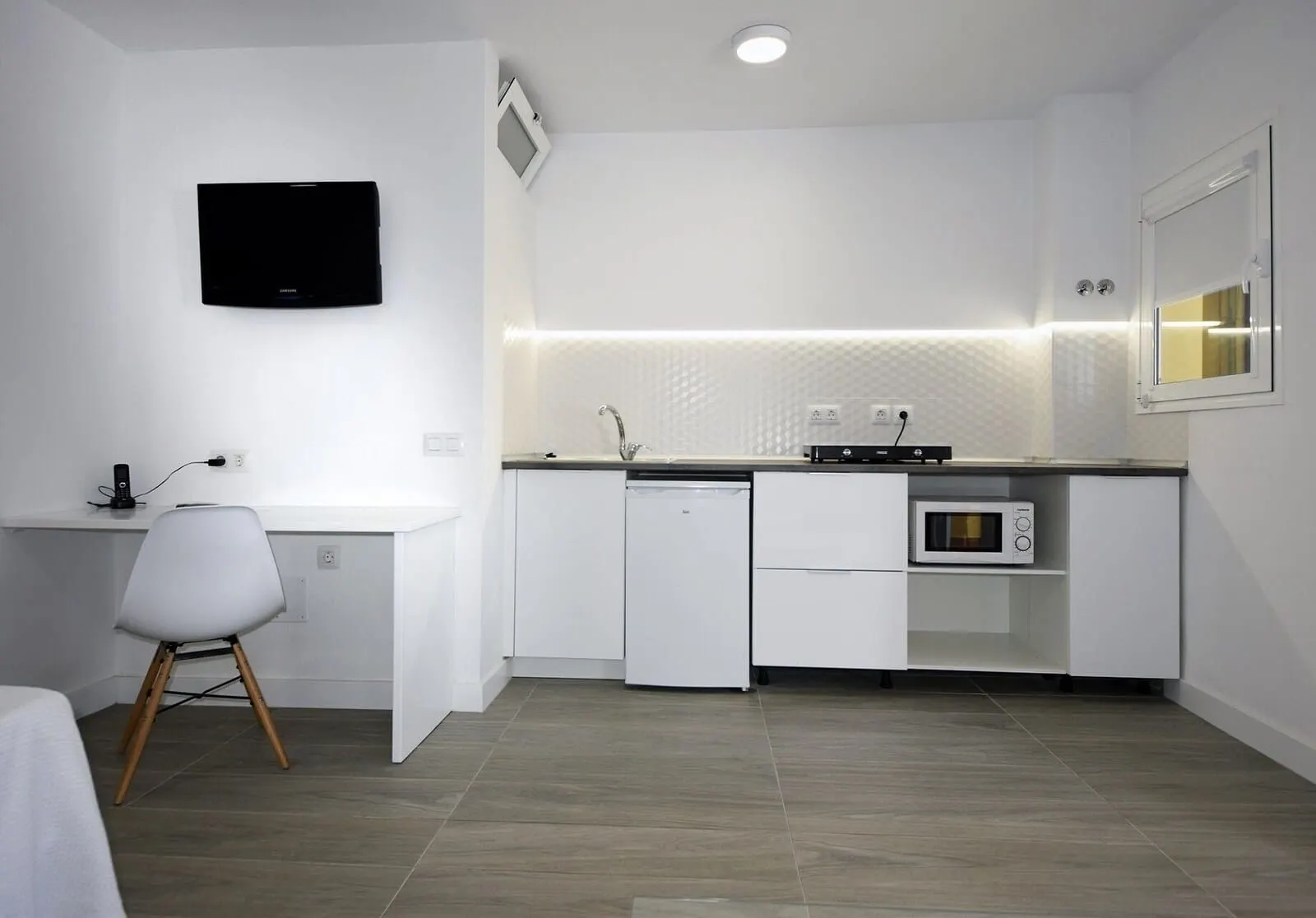 Skyview Hotel by LIVVO: A modern kitchen with white cabinetry, a built-in microwave