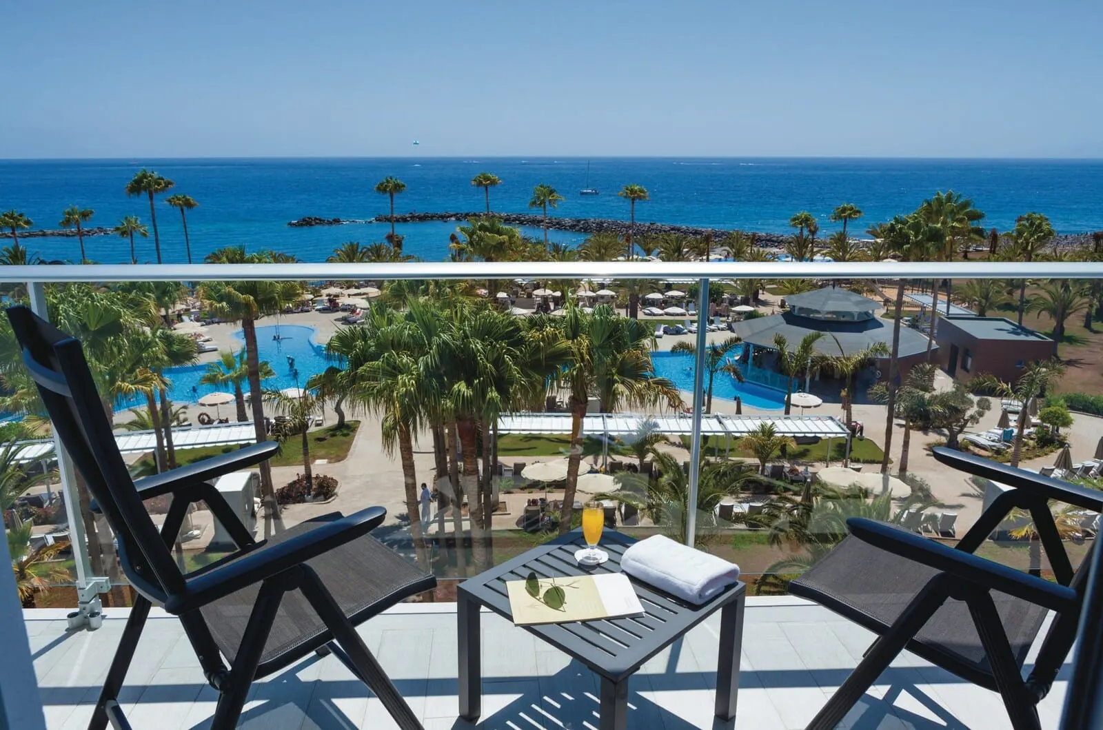 Hotel Riu Palace Tenerife: A balcony with two lounge chairs, a table with a drink and a menu