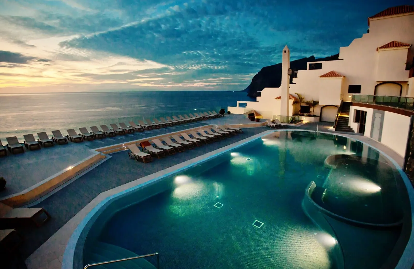 Royal Sun Resort: A pool with sun loungers and a view of the sea at sunset
