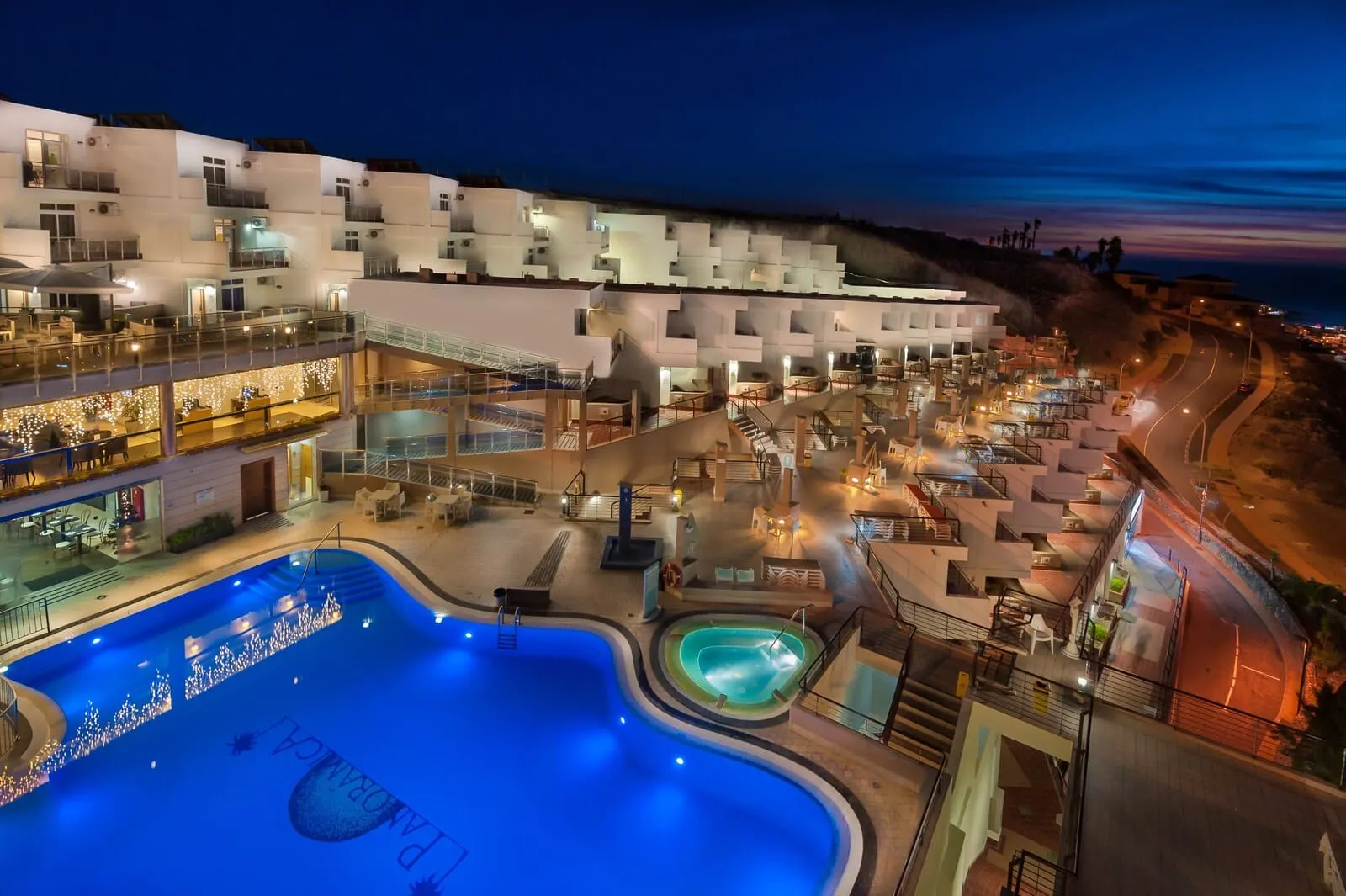 KN Aparthotel Panorámica: A hotel with multiple swimming pools, outdoor seating areas, and a well-lit terrace